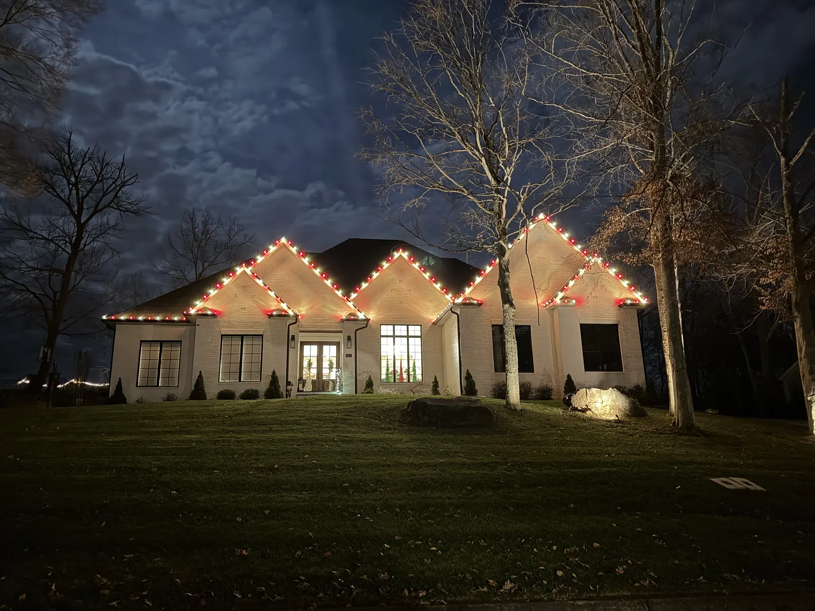 Red and warm white lights tracing a home’s roof peaks