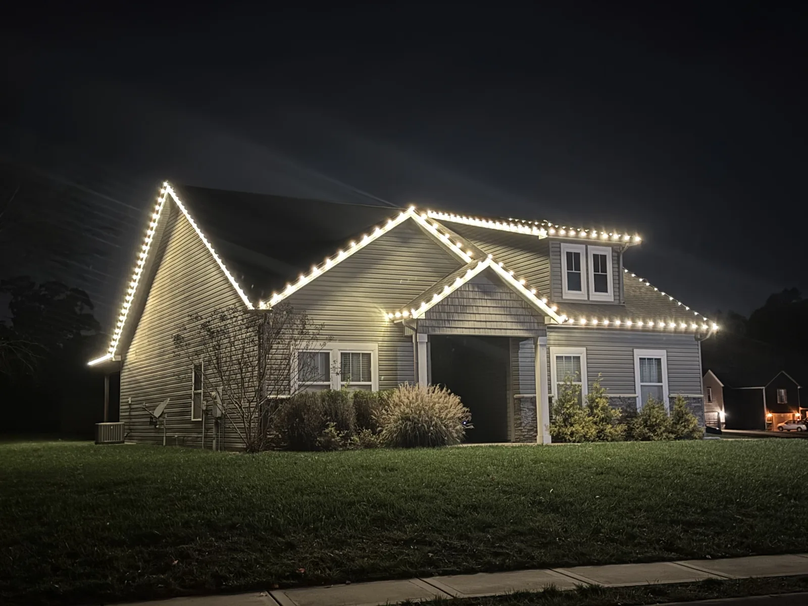 Warm white lights outlining a home’s front gables and roofline