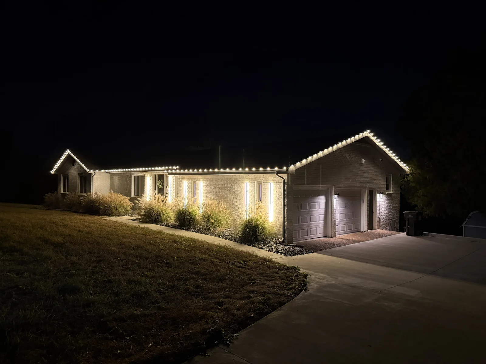 Warm white lights along a long home roofline and garage