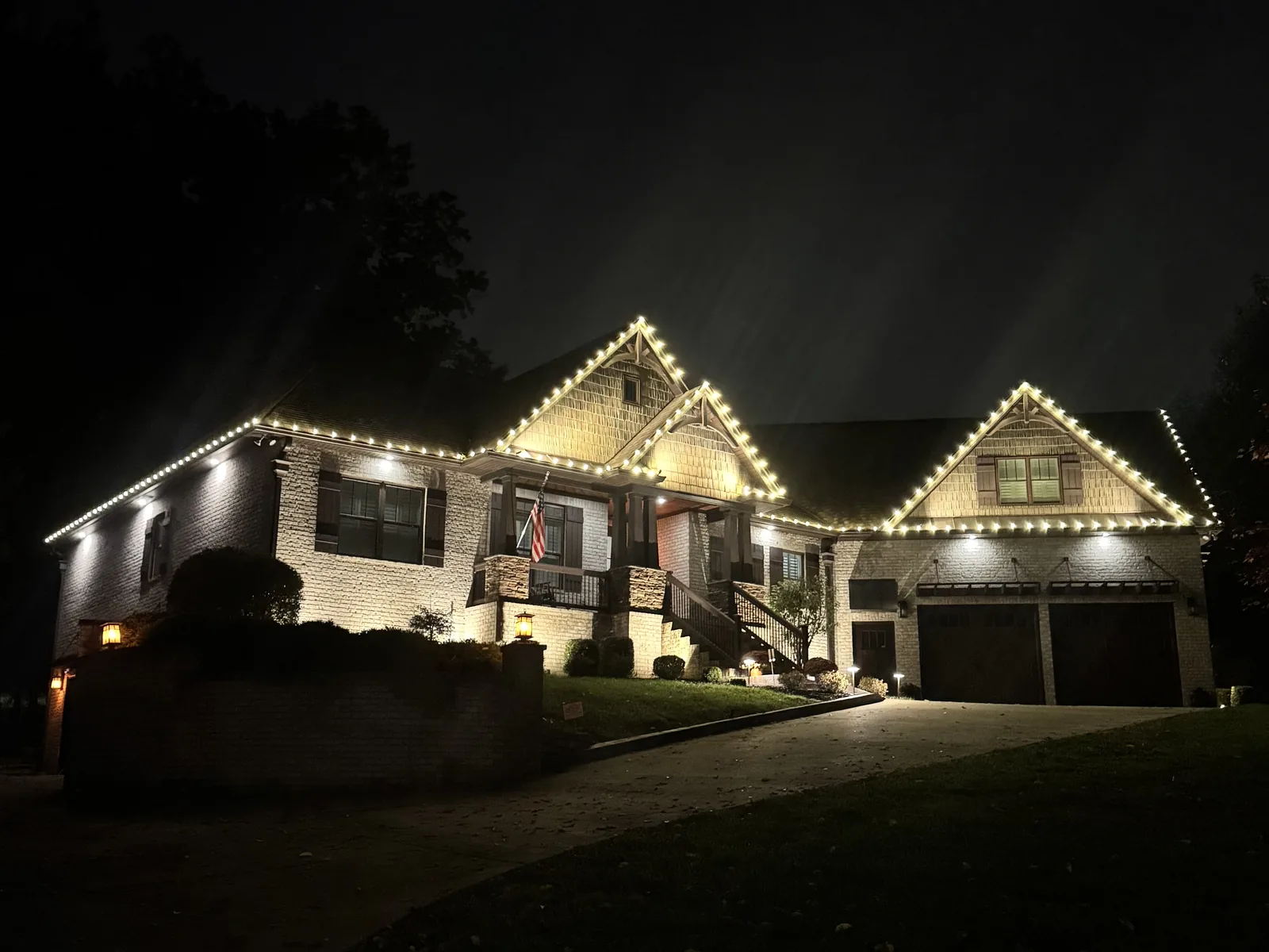 Warm white Christmas lights along several roof peaks of a home